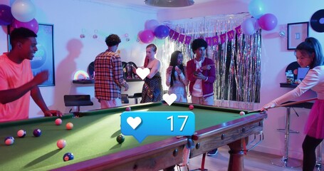 Playing friends leaning around green-felt pool table in rec room, woman in pink t-shirt holding cue