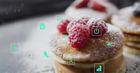 Showing small stack of pancakes topped with raspberries on dusted table, with floating eco icons