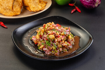 Fototapeta premium Spicy peanut and red onion salsa with cilantro and chili, served with fried chips.
