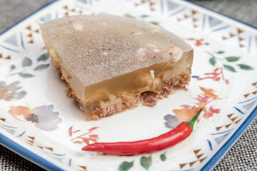 Closeup of authentic traditional Russian holodets (aspic jelly meat) served with mustard and fresh green onion, homemade food.