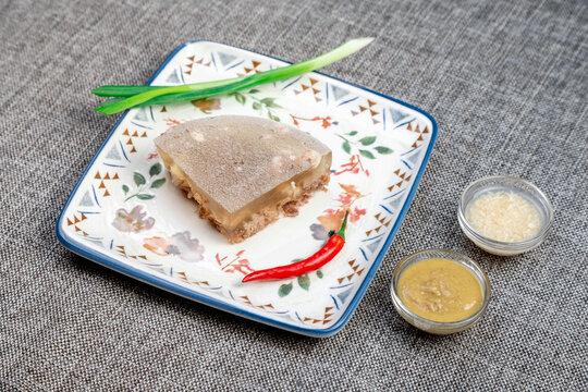 Closeup of authentic traditional Russian holodets (aspic jelly meat) served with mustard and fresh green onion, homemade food.