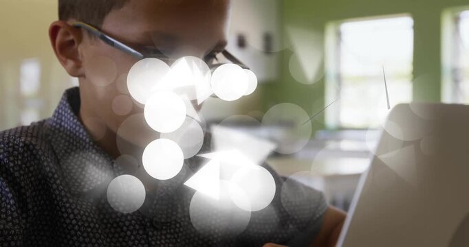 Boy placing hands on laptop, typing for schoolwork while animated shapes growing, partly hiding him