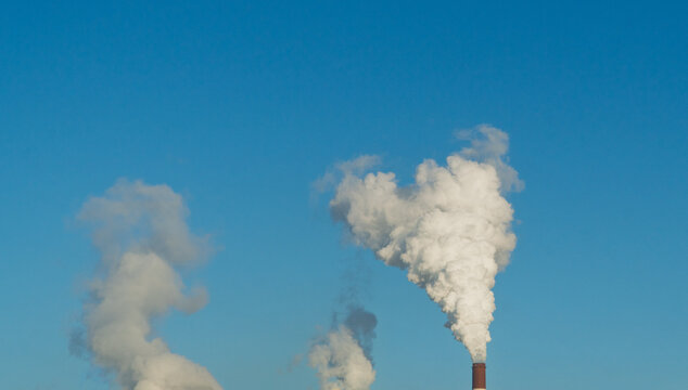CO2, greenhouse gases emissions. CHP emissions. Smoking chimney releasing smoke against a blue sky. Smoke from factory pipe of heat station in the city. Air pollution. Nuclear power plant cooling.