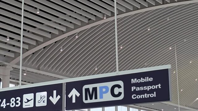 Blue sign at an international airport terminal directing passengers to the Mobile Passport Control lane for an expedited immigration and customs process, using a biometric security application