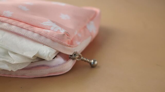 Close up of sanitary napkins in small pink pouch on table surface