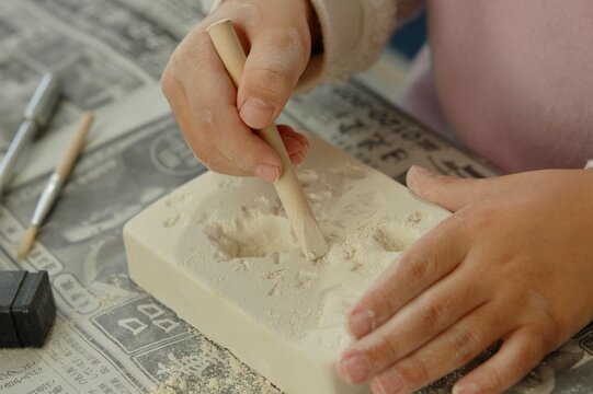 木の道具を使って石膏型から石を発掘するための子ども用セットで遊んでいる子どもの手元