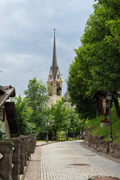 A Mountain Town Road Leads To Moena Church with Bell Tower - Italy