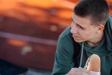 Teenager eating sandwich having outdoor lunch break
