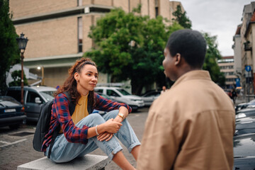 Two students talking together outdoors in urban setting