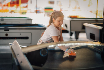 Girl playing air hockey in an arcade center with pool tables in the background