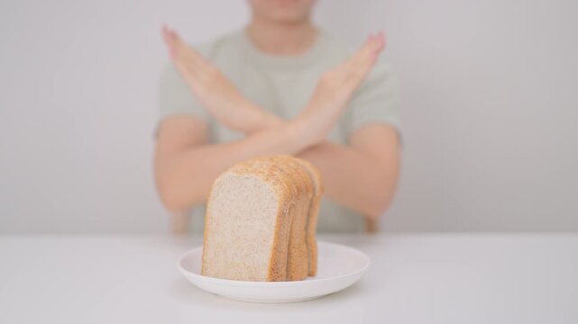 Unhappy woman showing Rejecting gesture and refusing to eat bread. concept of gluten intolerance, gluten sensitivity, carb loading concerns, or a disliking for unhealthy dietary habits