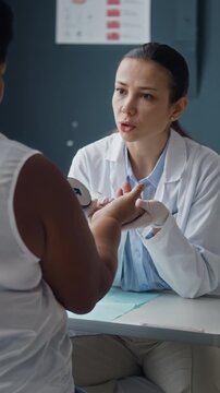 Vertical waist up of dermatologist performing dermatoscope skin examination on Black female patient inner palm during dermatology consultation