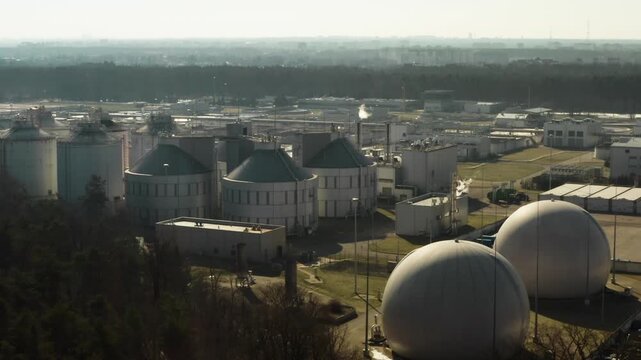 Large egg shaped digester tanks process sewage sludge to produce sustainable biogas and renewable energy while filtering urban liquid waste at metropolitan treatment facility infrastructure.