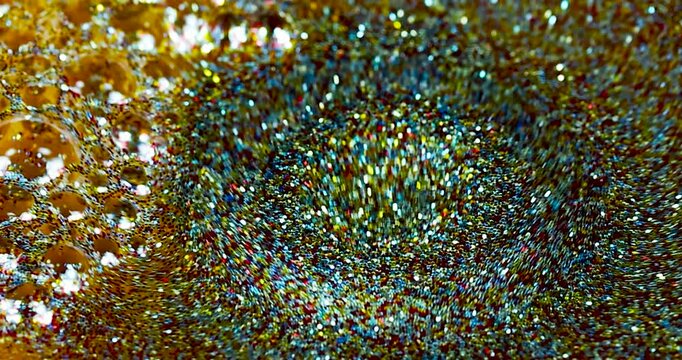 Gocce di emulsione con polvere di glitter colorata che cadono al rallentatore in una soluzione di acqua e glitter
