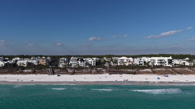Distant aerial view of a 30A area sandy beach coastline with modern white houses along the shore, Florida, USA