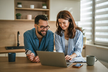Young couple managing household finances and online shopping together