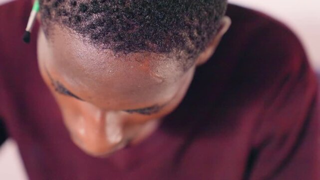 Man sketches with keen focus. Individual creating detailed artwork from elevated perspective. Focused artist carefully crafts intricate details while observing from above in studio setting