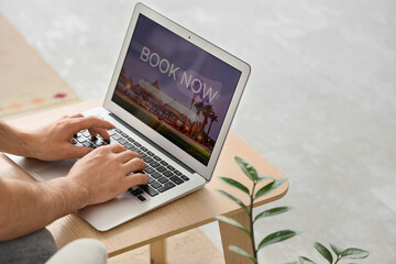 Young man using laptop to search for hotel room online at home, closeup