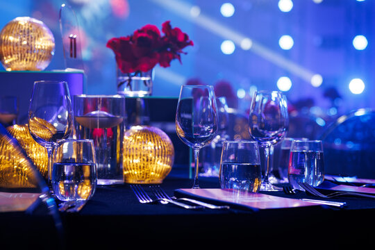 Elegant gala dinner table setting with red roses and blue ambient light