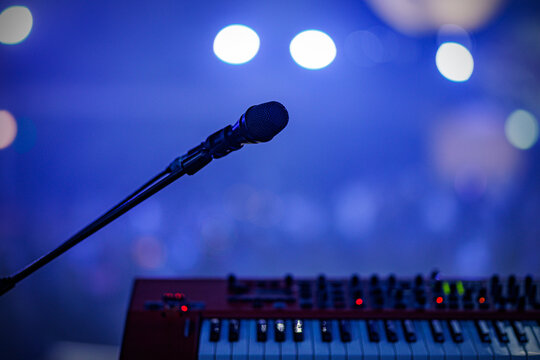 Microphone and electronic keyboard on stage with blue bokeh background