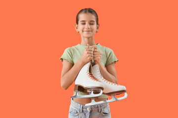 Dreamy teenage girl with ice skates on orange background