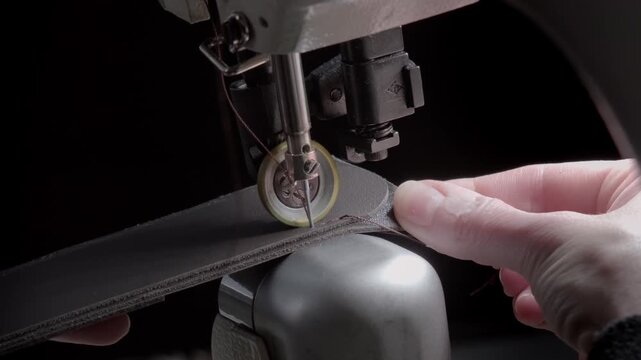 Close-up of an industrial sewing machine stitching leather belt