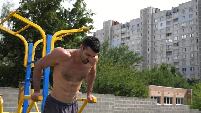 Sportsman performing intense workout on parallel bars, showcasing strength and determination through dynamic movements emphasizing muscular engagement and athleticism in a vibrant training environment