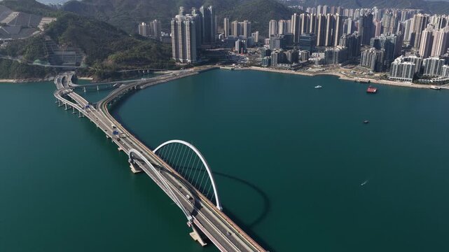 tunning aerial drone perspective of the Tseung Kwan O Cross Bay Link Bridge in Hong Kong, showcasing modern architecture, coastal transport infrastructure, and urban connectivity on a clear sunny day.