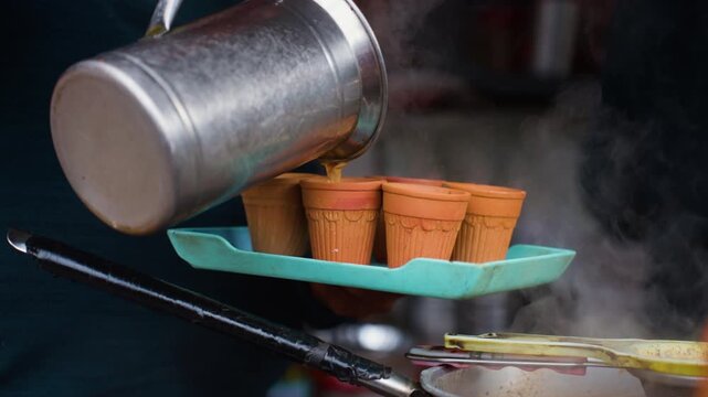 Street vendor pouring hot steaming Masala Nainital chai tea into traditional terracotta Kulhad cups