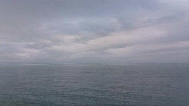 Wide seascape under overcast sky with gentle ocean movement.