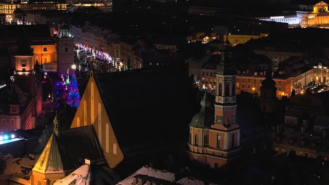 Festive aerial view of warsaw's old town at night. Beautifully illuminated historic buildings, a glowing christmas tree, and streets full of lights