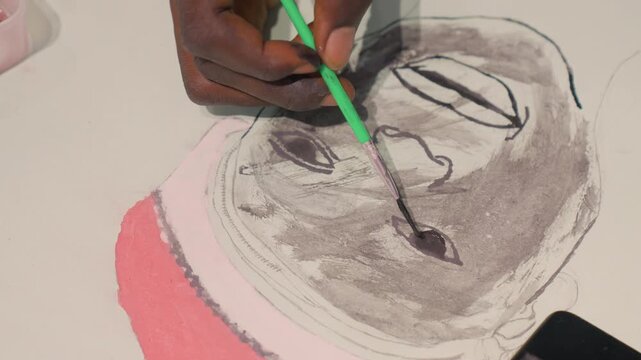 Tight black painting closeup, brush detailing facial shadows on black portrait, student blending washes with green brush, tablet reference, concentrated wrist motion, technical study