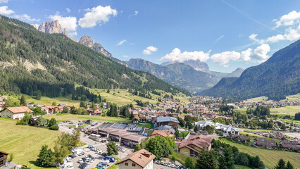 Fototapeta premium Aerial, bird view of Vigo di fassa, Val di fassa valley, Trentino, a town in the Italian dolomites. Sunny summer day. Mountain landscape. Dolomites. Beautiful travel destination.
