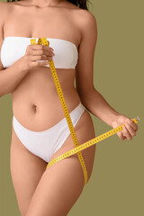 Beautiful young African-American woman with stretch marks on her body and measuring tape against...