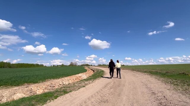 a loving couple walking through a field in summer