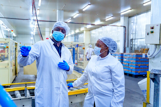 Workers discuss safety measures in a food processing plant during a busy shift