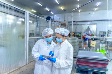 Workers check data on a mobile device in a food processing facility