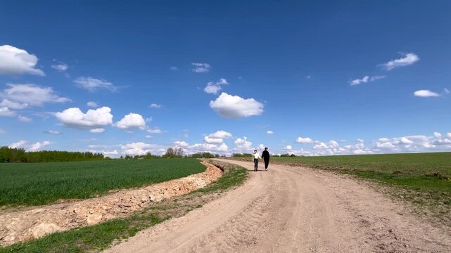 a loving couple walking through a field in summer