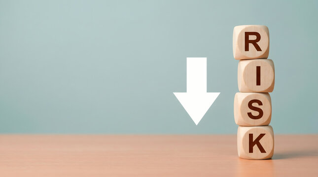 Wooden blocks stacked spelling RISK with a downward arrow, symbolizing risk reduction