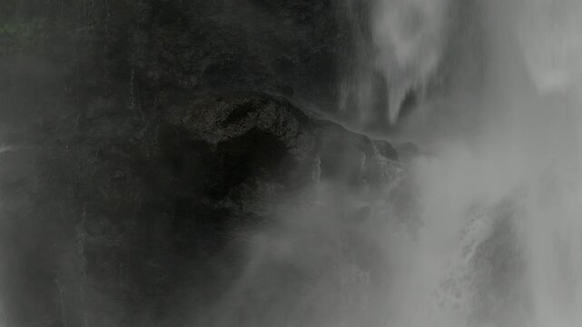 Close up view of wet cliff section covered by cascades of a large waterfall.