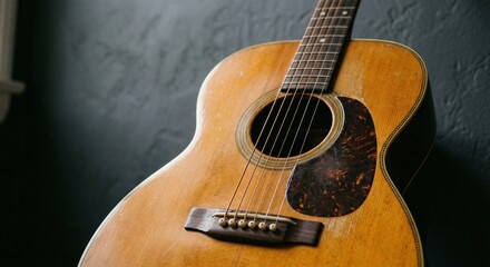 Obraz premium A close-up view of an acoustic guitar against a textured dark wall
