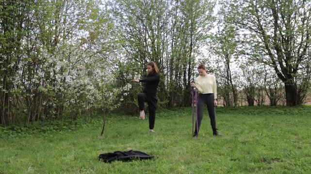A young couple doing sports outdoors, gymnastics and physical education exercises with a rubber band