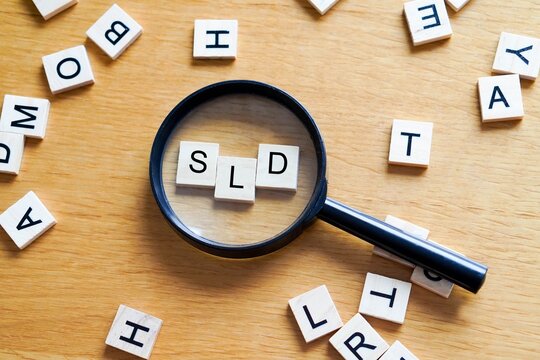 SLD, mental health and medicine concepts. Wooden letters with a magnifying glass on a wooden background