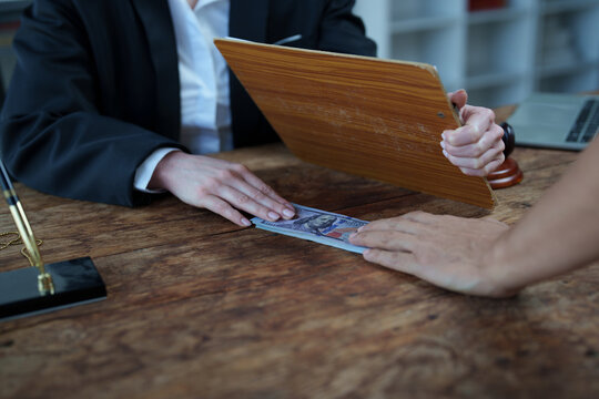 Two people exchange cash over a wooden desk in a clandestine backroom deal, evoking bribery, corporate corruption, illegal payments, and secret legal or business wrongdoing