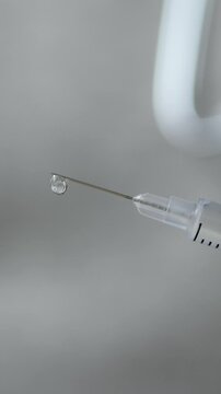 Sterile syringe hold vaccine with droplets on needle. Immunization as crucial protection against health risks. Medical advancement for disease control. Reliable vaccination procedures in healthcare