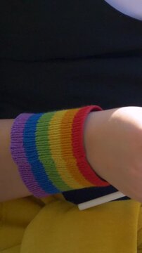 Female hand with rainbow wristband shows pride spirit. LGBT symbol of love rises as flag of equality. Gesture reflects unity, human rights and courage of community