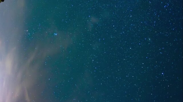 Dramatic 4K night time-lapse showing the movement of stars and Milky Way over a grove of trees and scenic mountain panorama, southern Europe.
