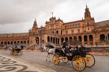 Naklejka premium Plaza de Espana, Sivilla. Historic stone building with towers and courtyard under cloudy sky