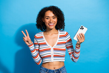 Young chic multiethnic woman smiling holding smartphone and posing for lifestyle photo