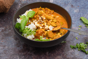 A vibrant vegan Thai red curry featuring tender seitan and fresh okra simmered in creamy coconut milk, garnished with cilantro and basil leaves